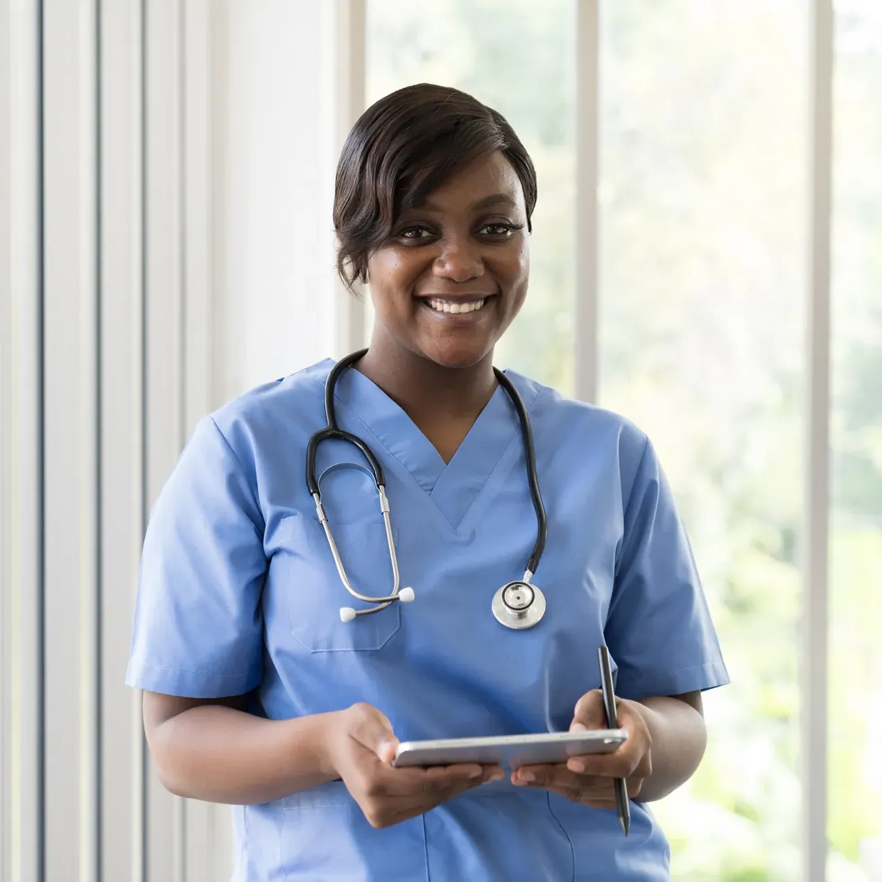 Herzing University medical assisting student smiling confidently with a stethoscope and tablet in hand, symbolizing readiness for healthcare careers.